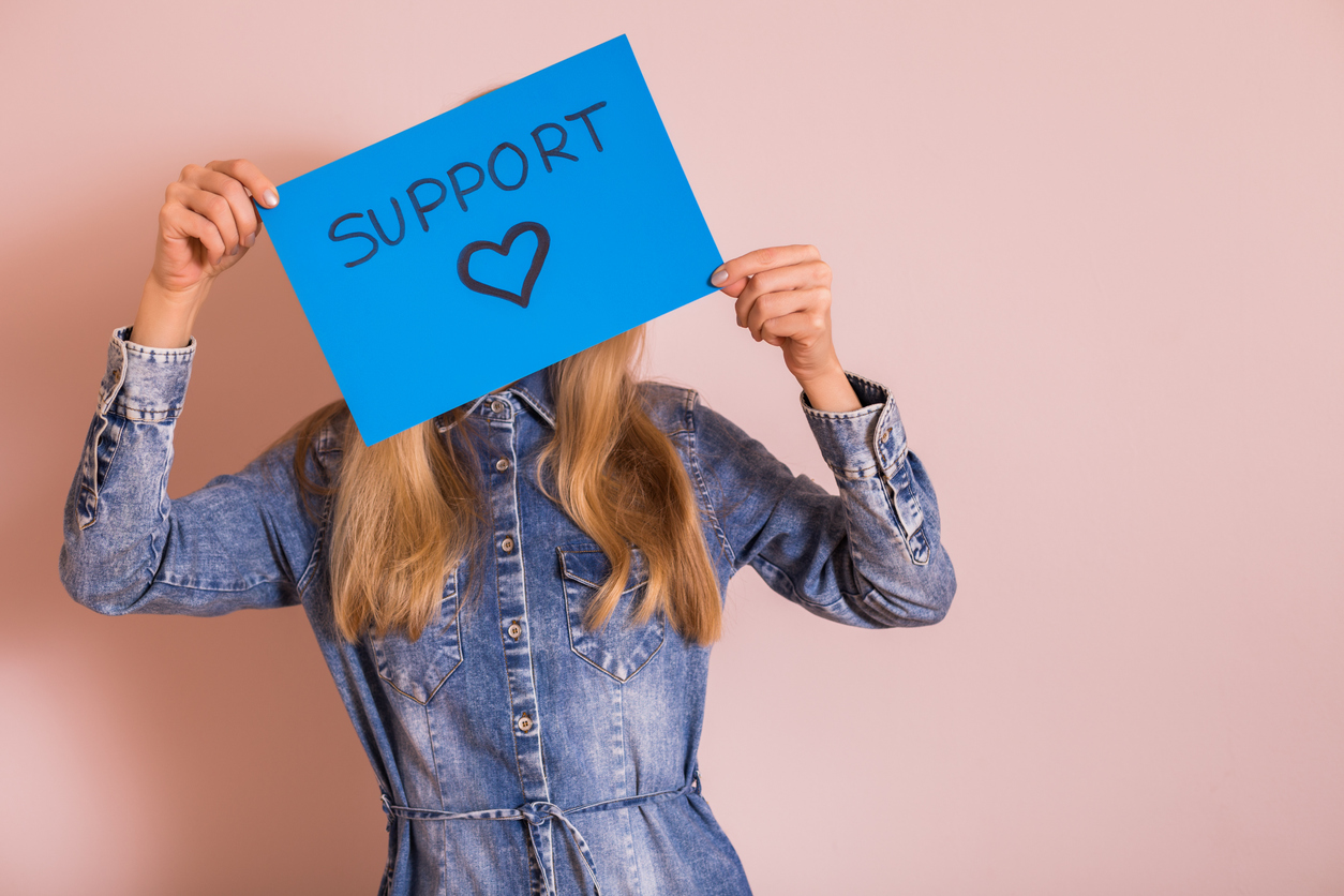 A person holding a sign that says Support with a heart